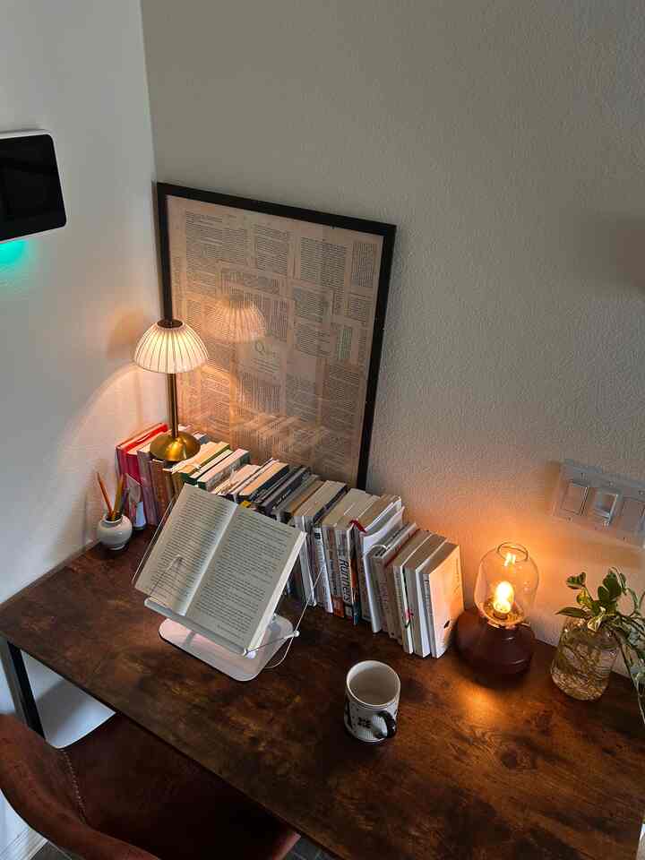 Cozy study corner with white walls and brown wooden desk, featuring lamps and books for focused reading