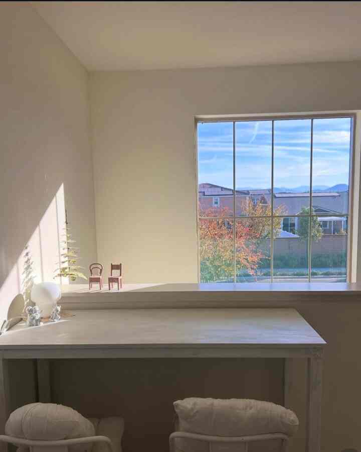 Beige-toned study nook with a large window and simple desk, creating a quiet and warm meditation space
