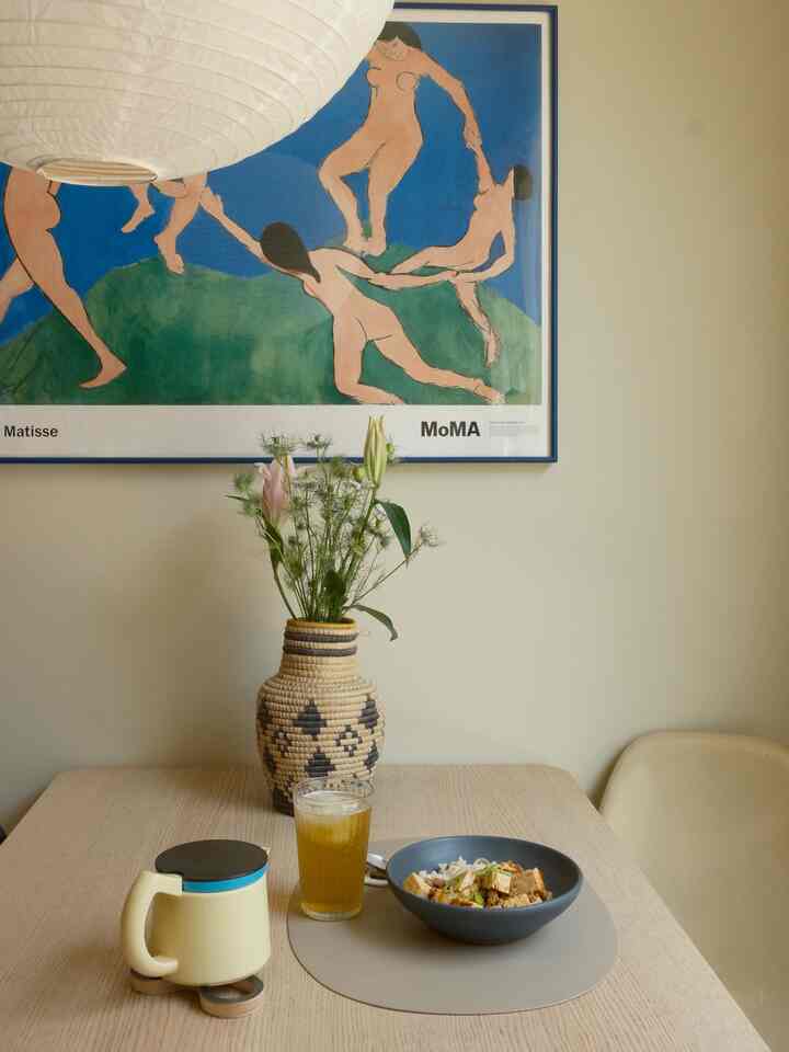 Beige toned dining room with wood-tone table and large Matisse poster creating a simple aesthetic