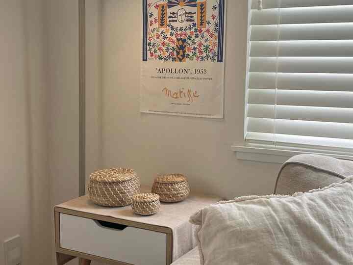 White and wood tone living room featuring a natural nightstand and a set of rattan storage baskets in a cozy space