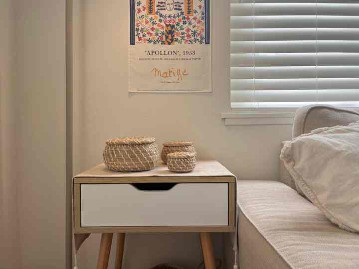 Natural brown and white toned living room corner featuring a side table with woven baskets and a cozy sofa with a simple warm atmosphere
