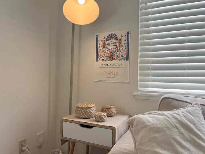 White and beige toned living room corner featuring rattan decor and a floor lamp, with a cozy and simple atmosphere