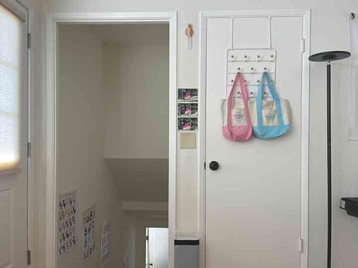 White and beige tone entrance featuring a door with multi-use organizer and a floor lamp creating a clean space