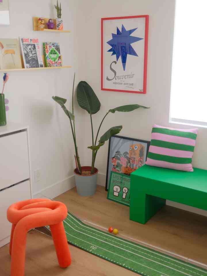 Bright green and orange accent small indoor space featuring plant, bench, and stool with cozy retro vibe