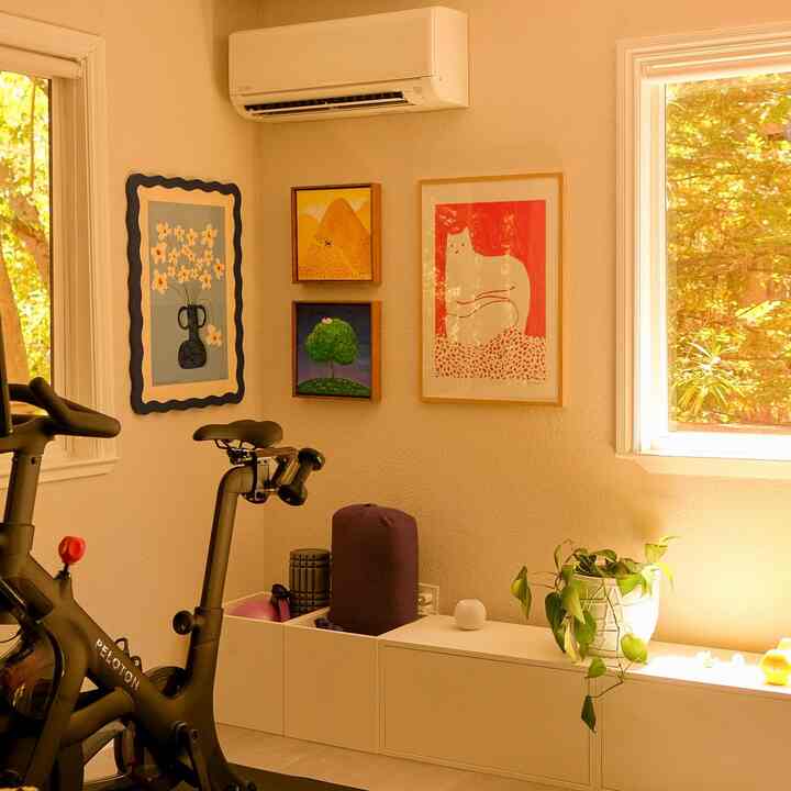 Warm beige-toned home gym corner featuring white cabinets and cat artwork creating a cozy atmosphere