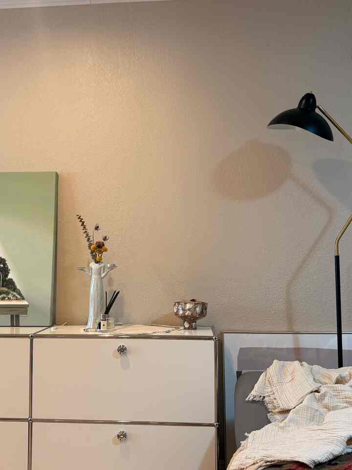 Beige and white toned wall with sideboard and floor lamp arranged in a cozy natural modern living room corner space