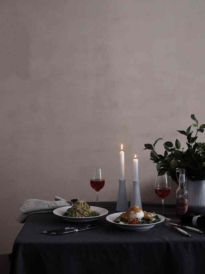 Dark gray tablecloth dining table featuring two candles, wine glasses, and dishes creating a calm home cafe dining atmosphere