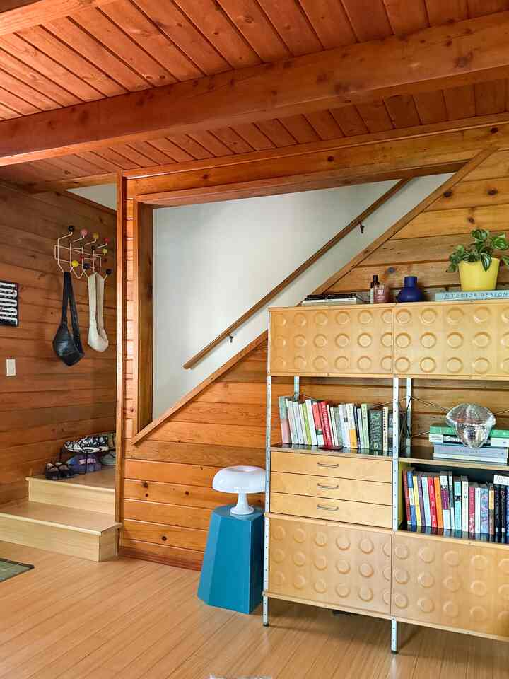 Cozy Nordic-style space with natural wood-tone walls and stairs, featuring a bookshelf and ambient lighting