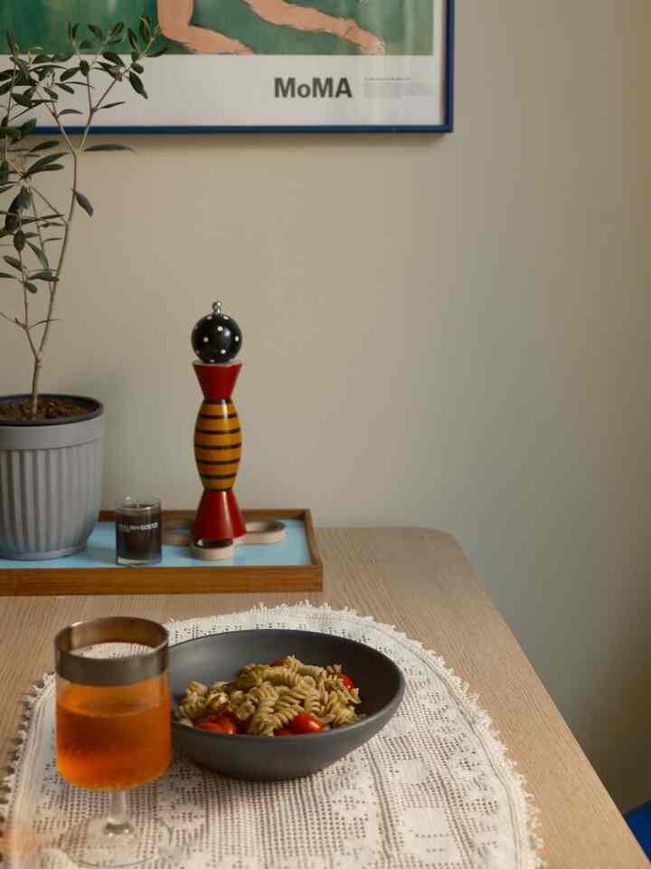Natural color and beige toned dining room with a table featuring a bowl of pasta and a glass of drink creating a cozy atmosphere