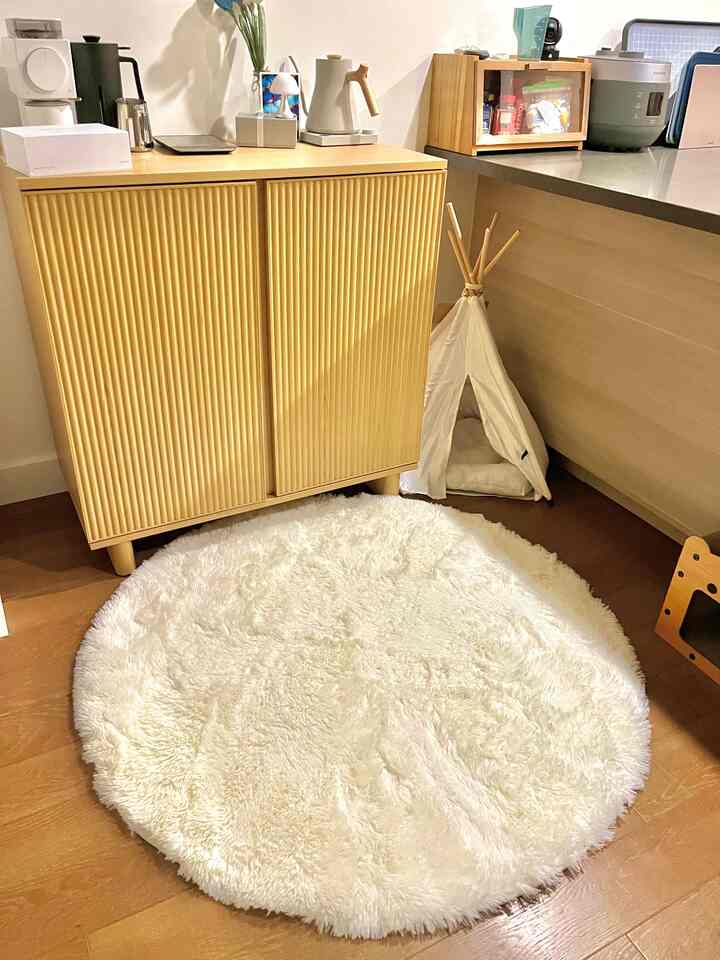 Yellow and white toned apartment kitchen corner featuring cozy cat teepee, pet house, and soft round rug creating a warm space