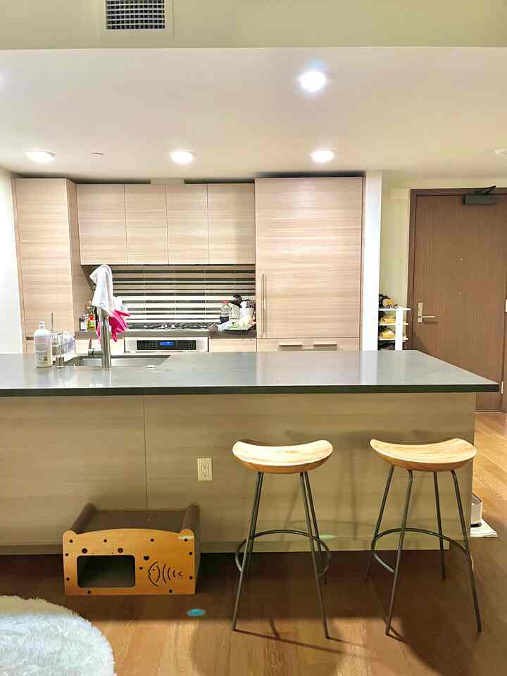 Warm wood tone kitchen featuring a pet house for cats and two bar stools in a cozy living space