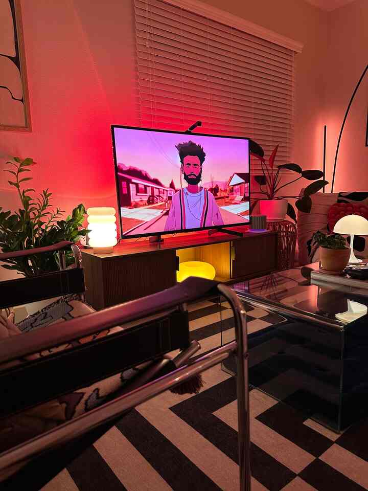 Red-lit modern living room featuring a TV stand, leather sofa, glass coffee table, and ambient stylish atmosphere