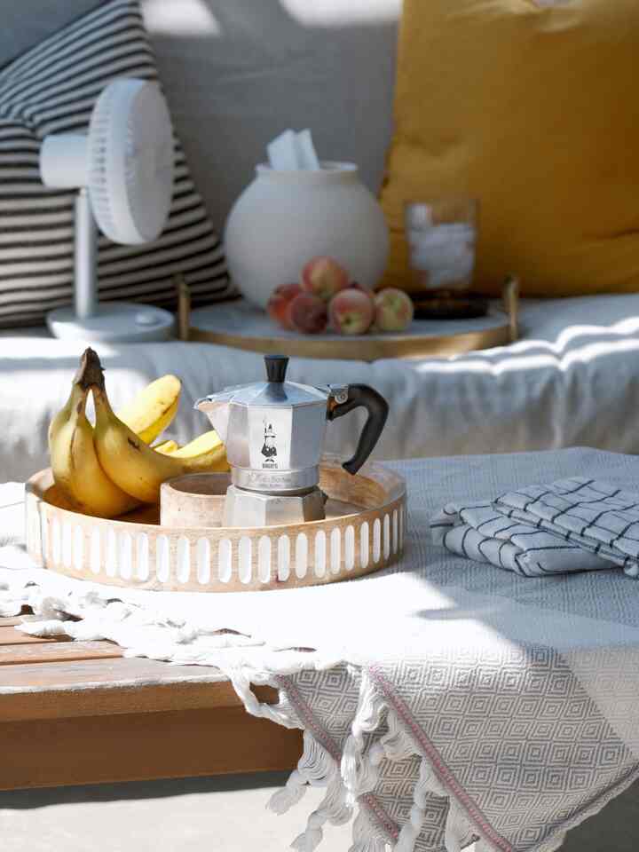 White and beige toned living room featuring a tray with coffee maker and bananas, creating a cozy home cafe atmosphere