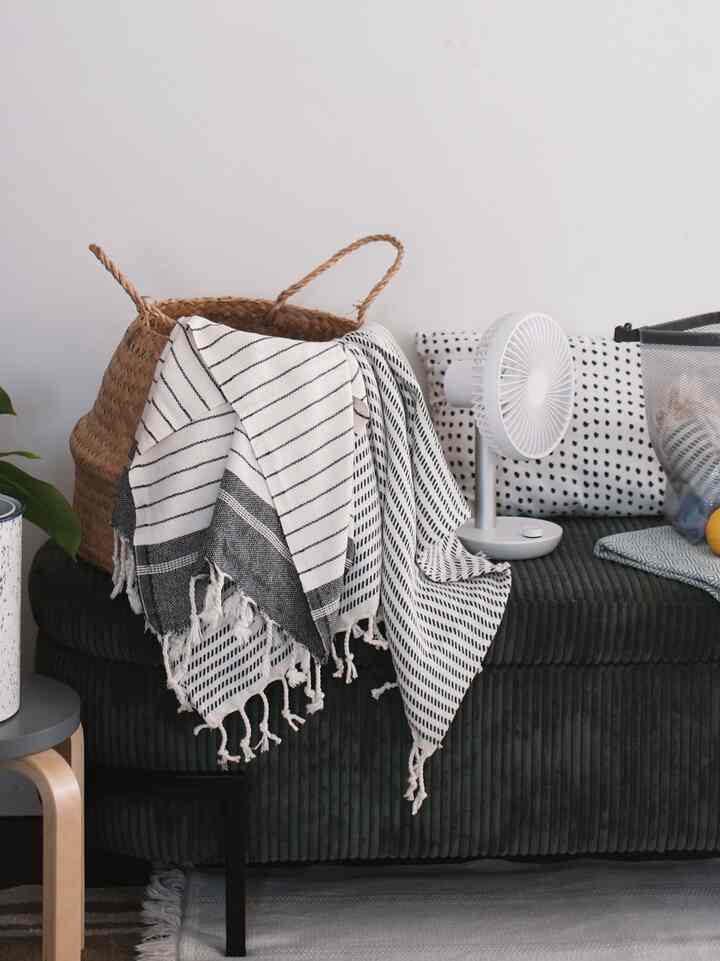 Natural tone entrance area featuring dark green ottoman, Turkish towels draped on basket, and a white fan creating a cozy interior