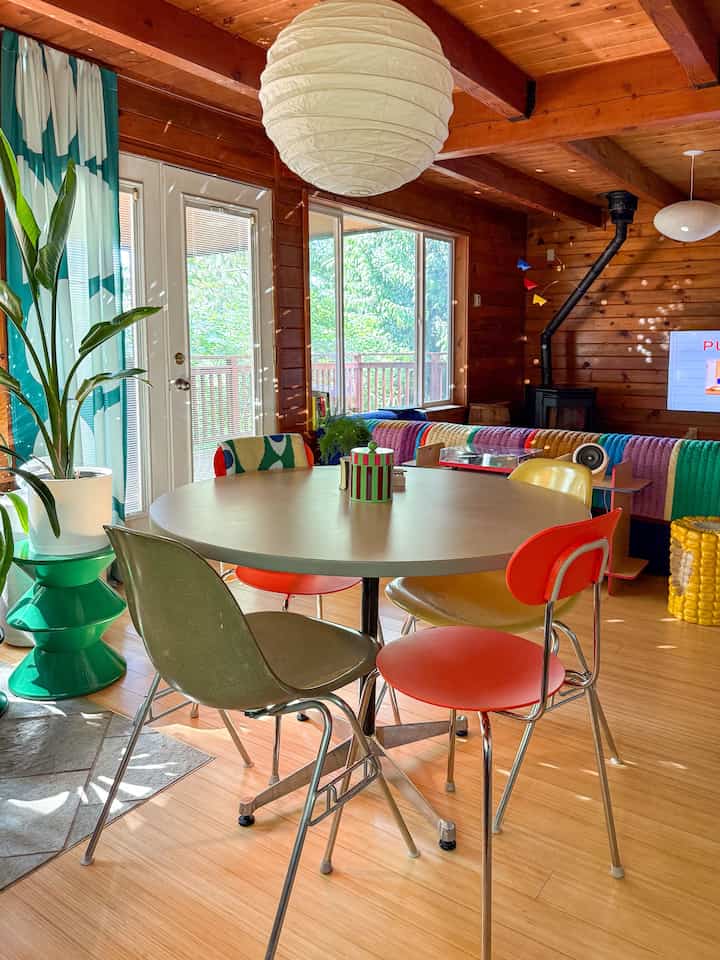 Warm wood tone dining room featuring a round dining table and colorful chairs, creating a cozy atmosphere