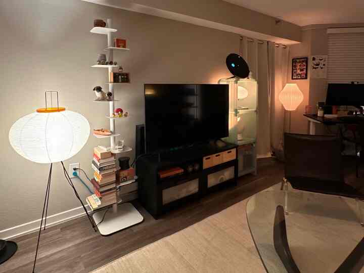 A modern living room in white and natural tones featuring a TV stand and floor lamps