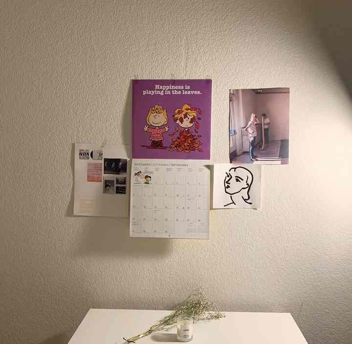 White-toned simple room wall featuring Snoopy calendar and various wall decor with a warm atmosphere