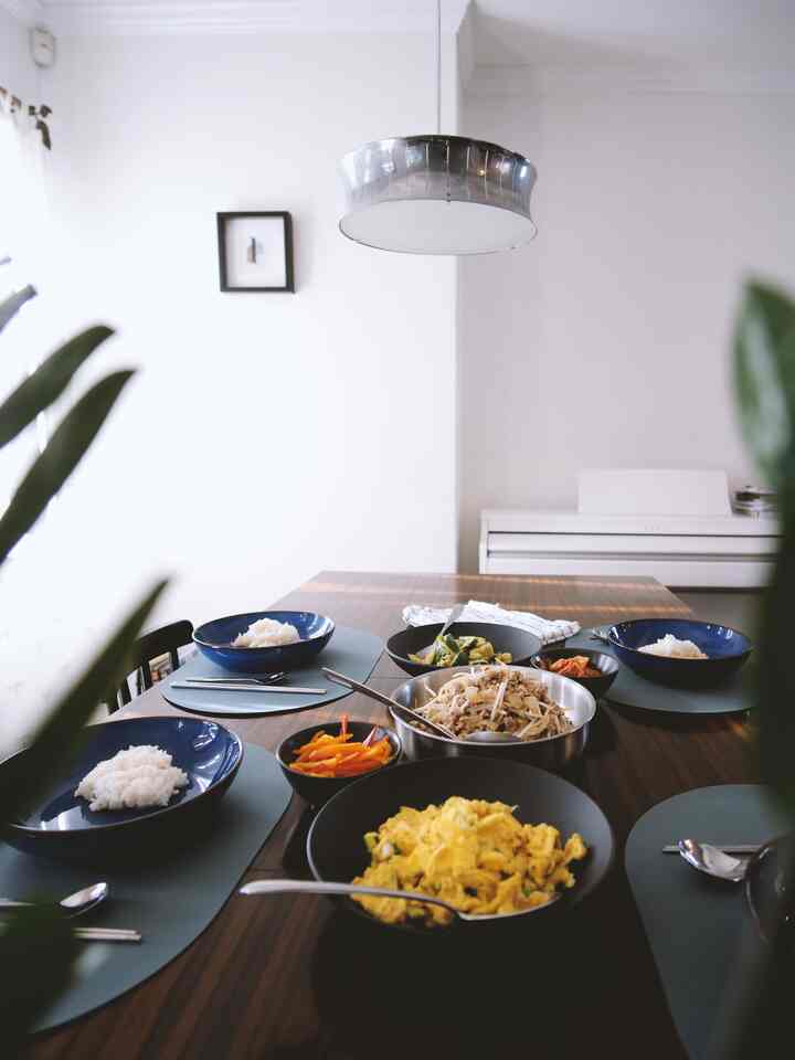 Bright, clean modern dining room with wood-toned table featuring diverse bowls and tableware setup