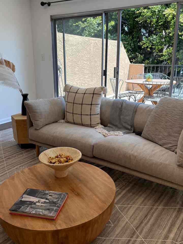 Natural color and wood tone living room featuring beige sofa and round coffee table, creating a cozy atmosphere
