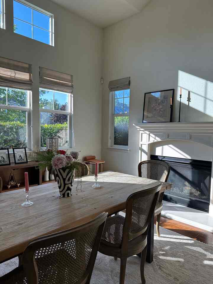 Bright and spacious dining room with white walls, wood-tone dining table, fireplace, and candles in a simple layout