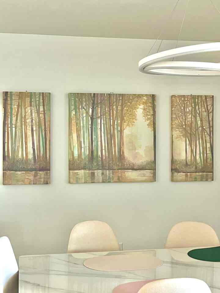 White and natural toned dining room featuring placemats on table and forest wall art in a simple setting