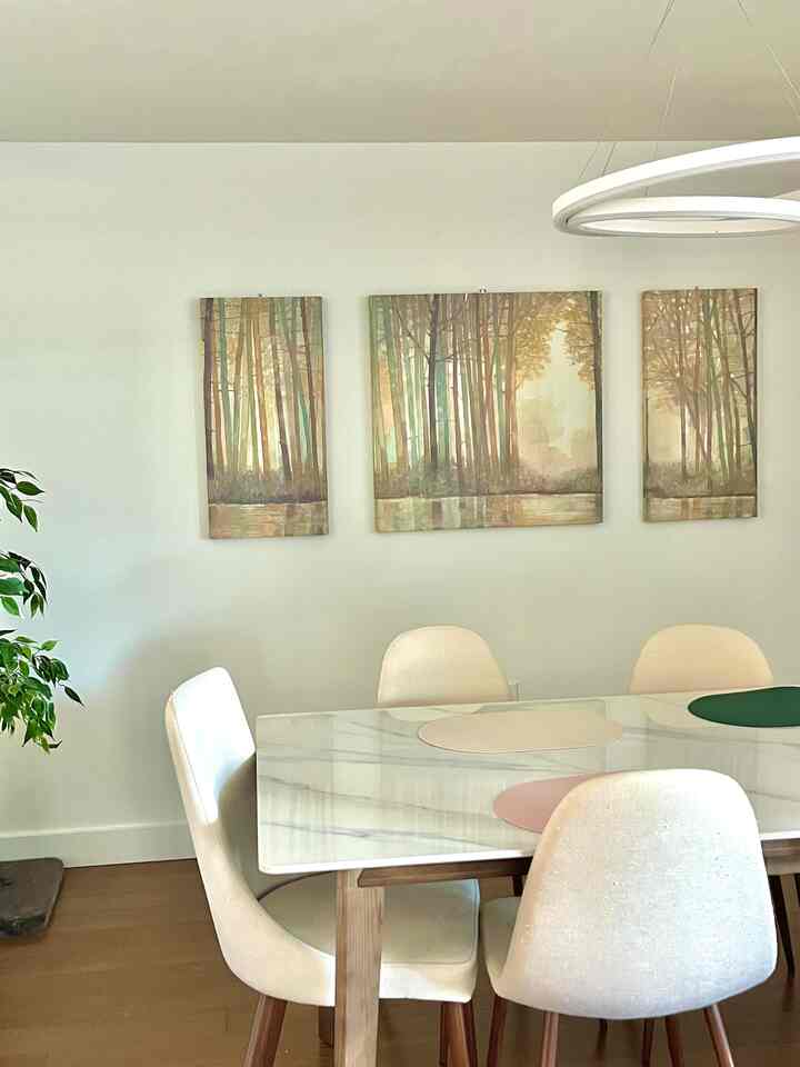 Simple dining room with soft natural tones, featuring white walls, wooden dining table and neutral placemats centrally placed