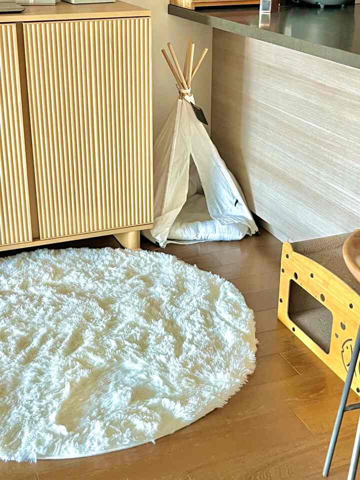A white and wood-toned kitchen corner featuring a round faux fur rug and a pet teepee creating a cozy atmosphere