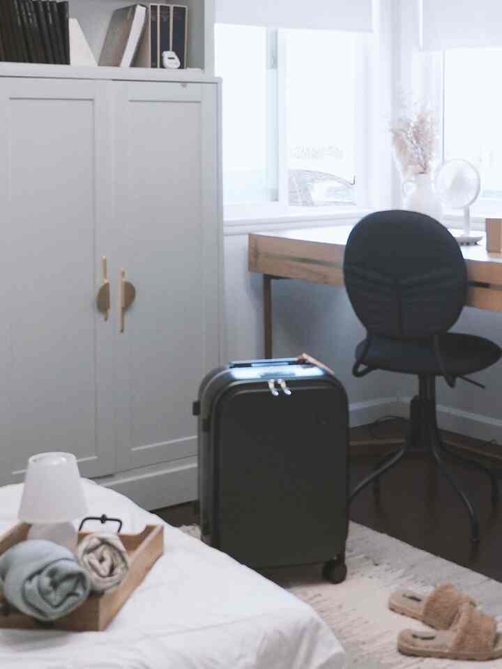 White-walled mid-century modern home office and guest room featuring wood tone desk and sofa bed setup