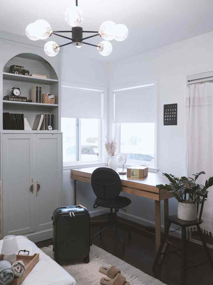 A compact home office with white walls and wood tones featuring a desk and office chair in a neat layout