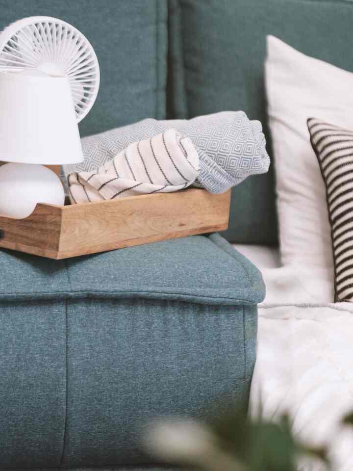 Blue and white toned home office and guest room featuring sofa bed with wooden tray holding towels and lamp, creating a cozy atmosphere