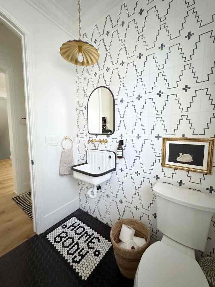 White and black tiled bathroom featuring a gold scalloped pendant light and wall decor with a stylish, modern atmosphere