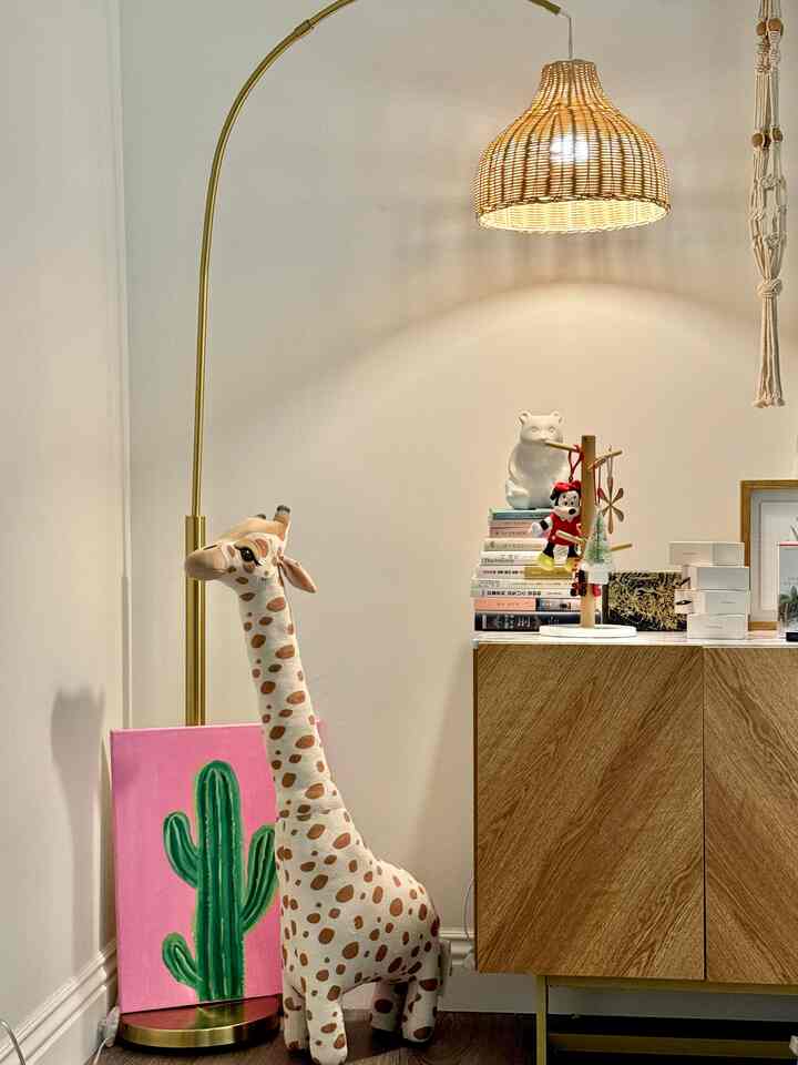 Natural color bedroom corner featuring floor lamp and giraffe soft toy with a cozy atmosphere