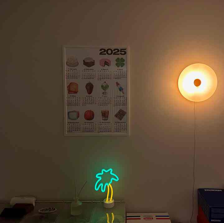 Modern interior with white walls and yellow circular wall lamp, featuring neon palm tree light at lower center