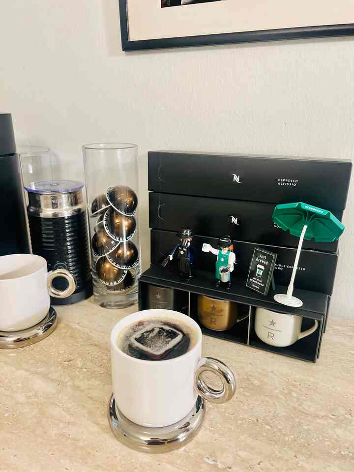 White and silver toned home cafe space featuring Nespresso coffee capsules and cups on cozy table