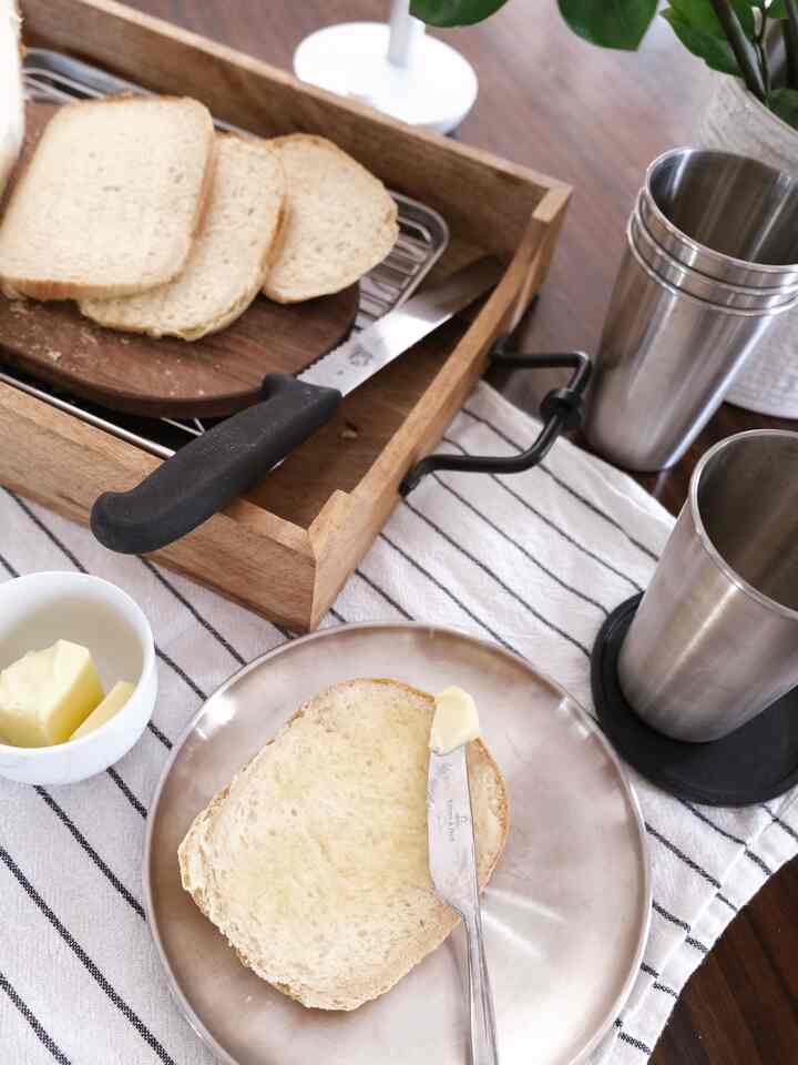 Natural wood and white-accented dining table featuring freshly sliced bread and butter for a simple breakfast setting