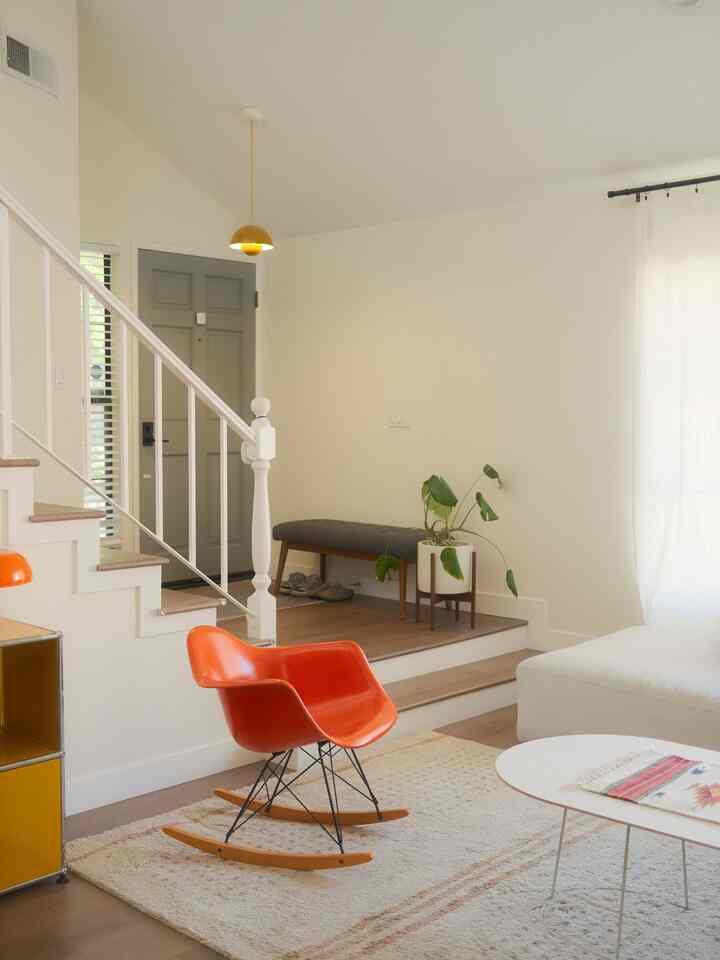 Bright white-toned living room with white sofa and orange mid-century modern armchair