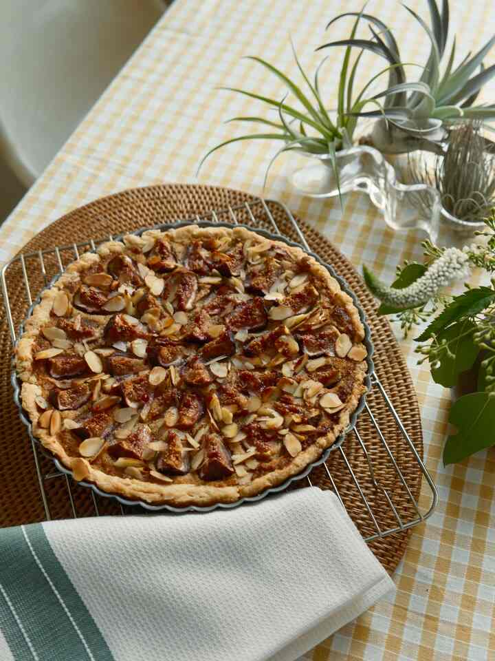Natural tone home party setting with homemade fig tart on bright yellow gingham tablecloth