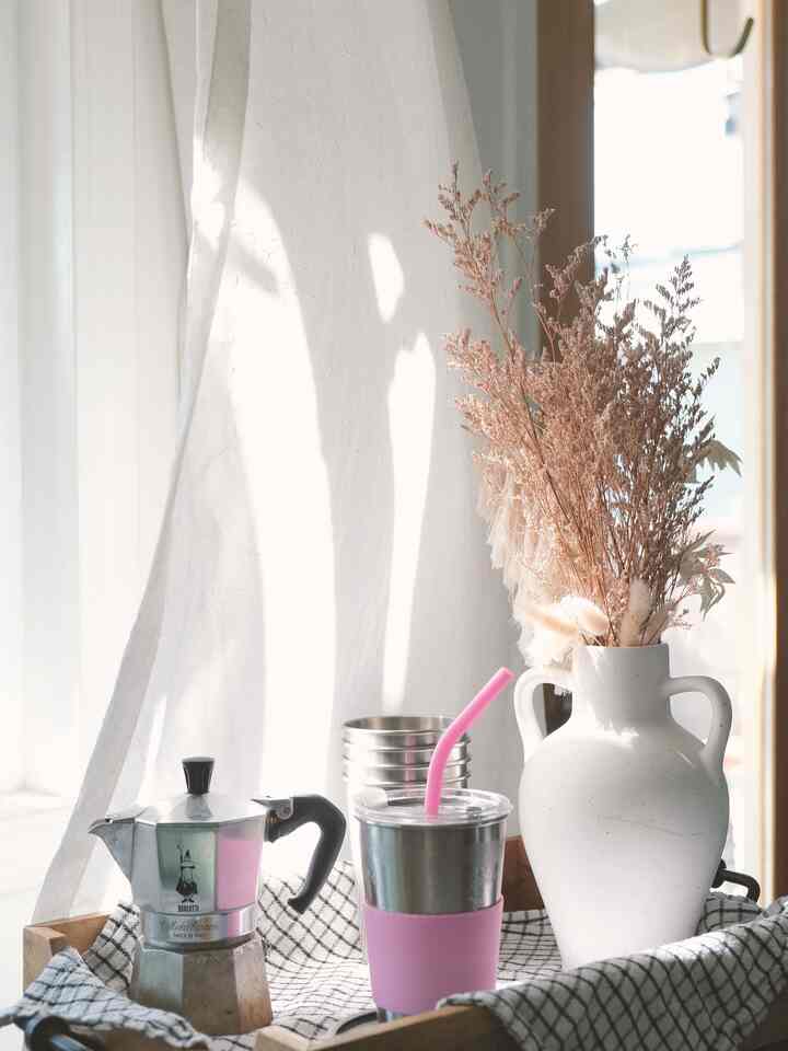 Soft pink and silver toned home cafe scene featuring a wooden tray with coffee equipment and dried flowers, creating cozy kitchen vibes