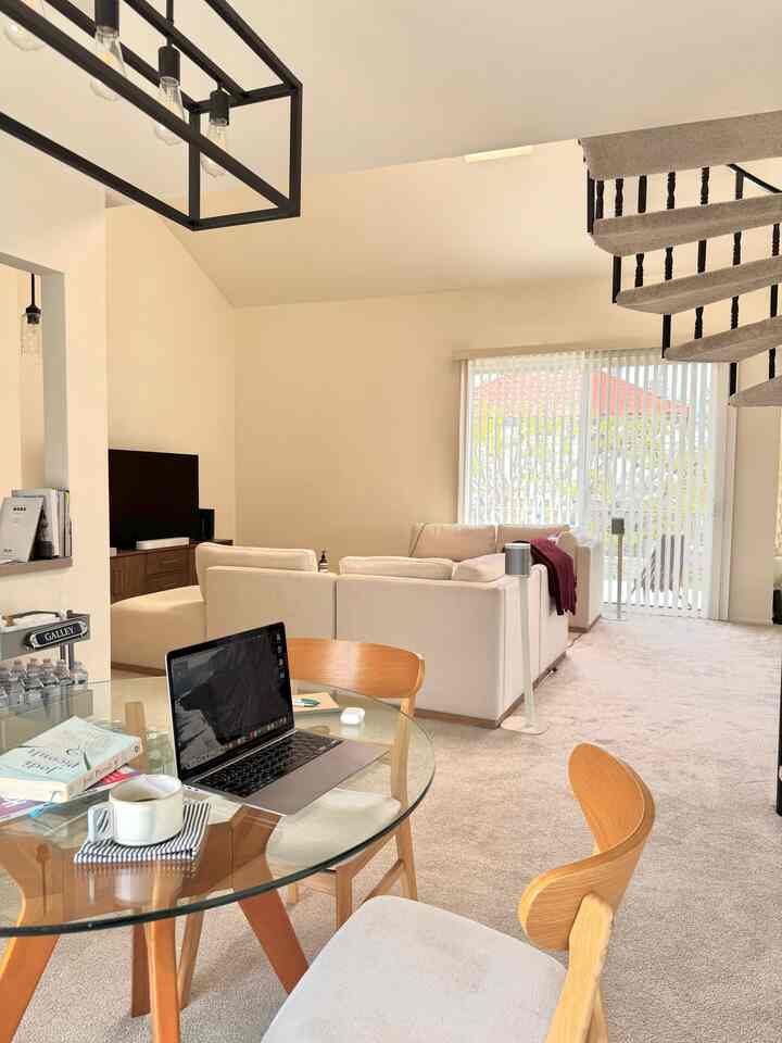 Modern living room combined with home office in white and wood tones, featuring glass dining table and sofa