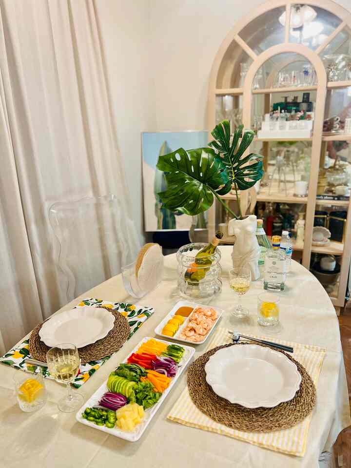 White tablecloth covered dining room with natural color table, cozy space featuring colorful plates and chilled drinks for a home party