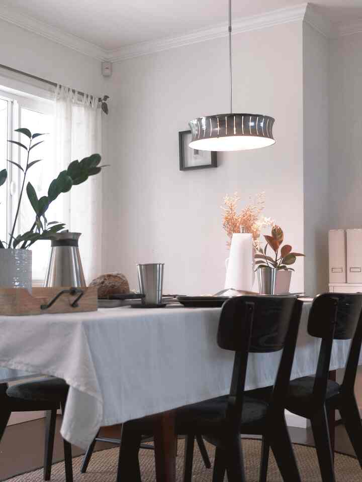 White-toned dining room featuring black dining chairs and floral decorations on the table, creating a clean atmosphere
