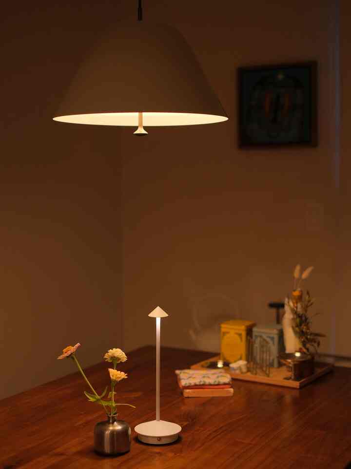 Warm wood tone dining room featuring a dining table with a table lamp and vase, creating a cozy atmosphere