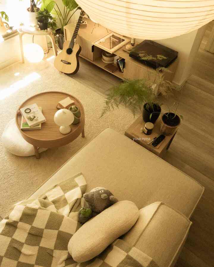 Beige and wood toned warm living room featuring a sofa, round coffee table, and plants creating a natural atmosphere
