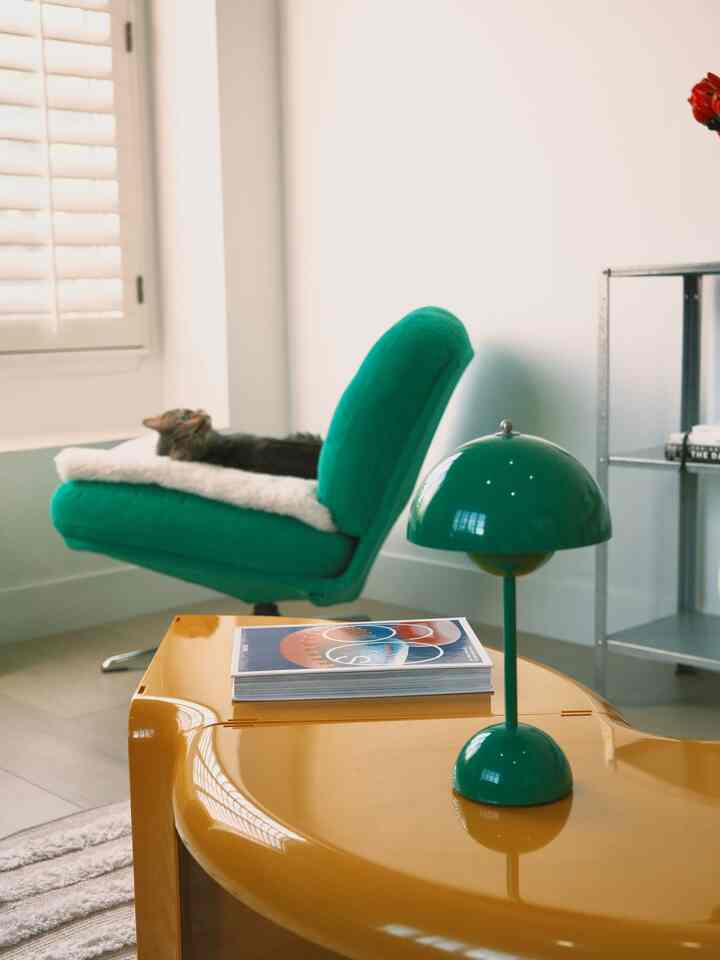 Natural color tone living room featuring a green armchair and table lamp on a yellow coffee table creating a cozy atmosphere