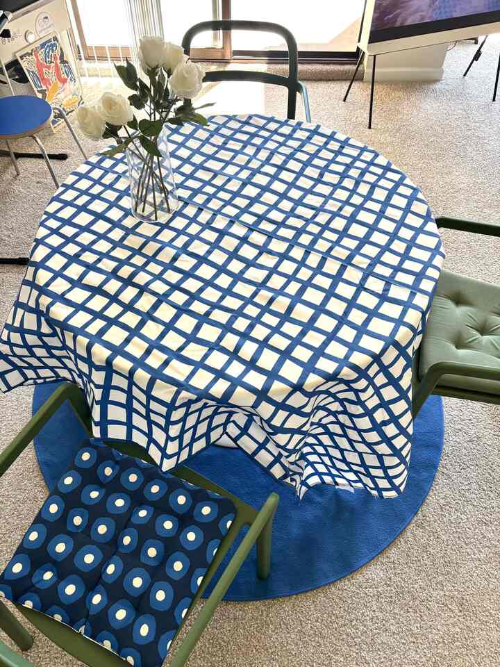 Navy and blue toned dining room featuring a blue checkered tablecloth and green dining chairs in a cozy setting