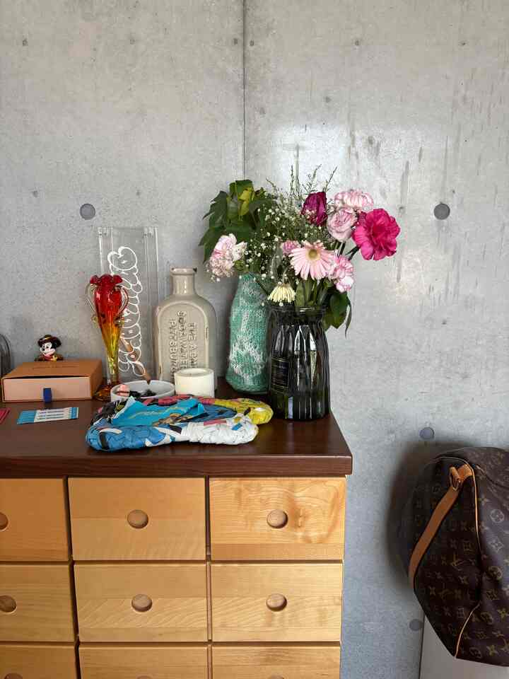 ナチュラルカラーのチェストがあるモダンな空間、透明な花瓶と多様な花が飾られた整ったインテリア