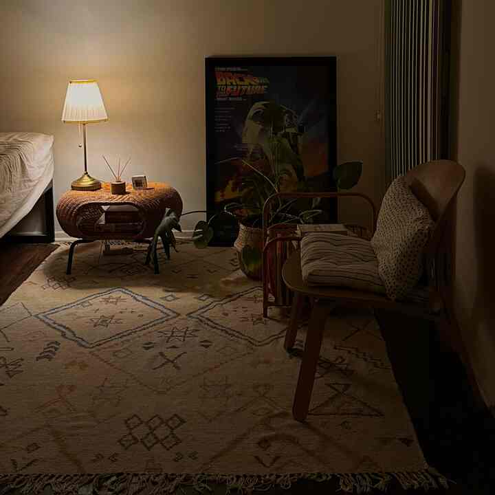 Warm beige-toned bedroom featuring rattan stool and patterned rug with a cozy ambient atmosphere