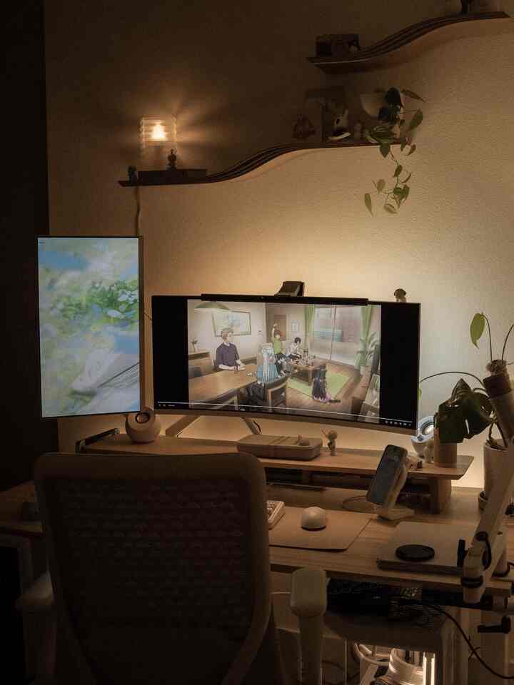 Warm beige and wood tone home office featuring a desk and chair with dual monitors and plants, cozy anime viewing setup