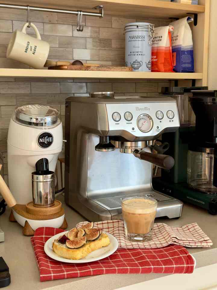 Warm beige and red toned kitchen home cafe space featuring espresso machine and coffee grinder on a cozy coffee bar