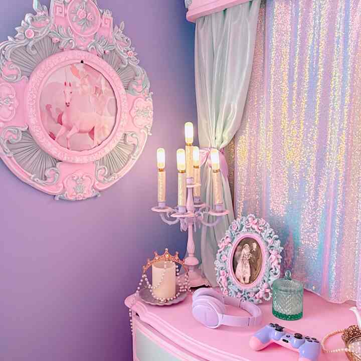 A bedroom with purple walls and a pink console table featuring vintage-style candelabra, curtains, and a game controller creating a cozy atmosphere